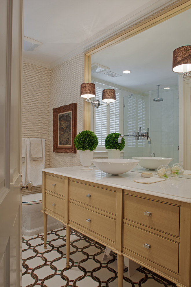 Modelo de cuarto de baño clásico con lavabo sobreencimera, puertas de armario de madera oscura, paredes beige y armarios con rebordes decorativos