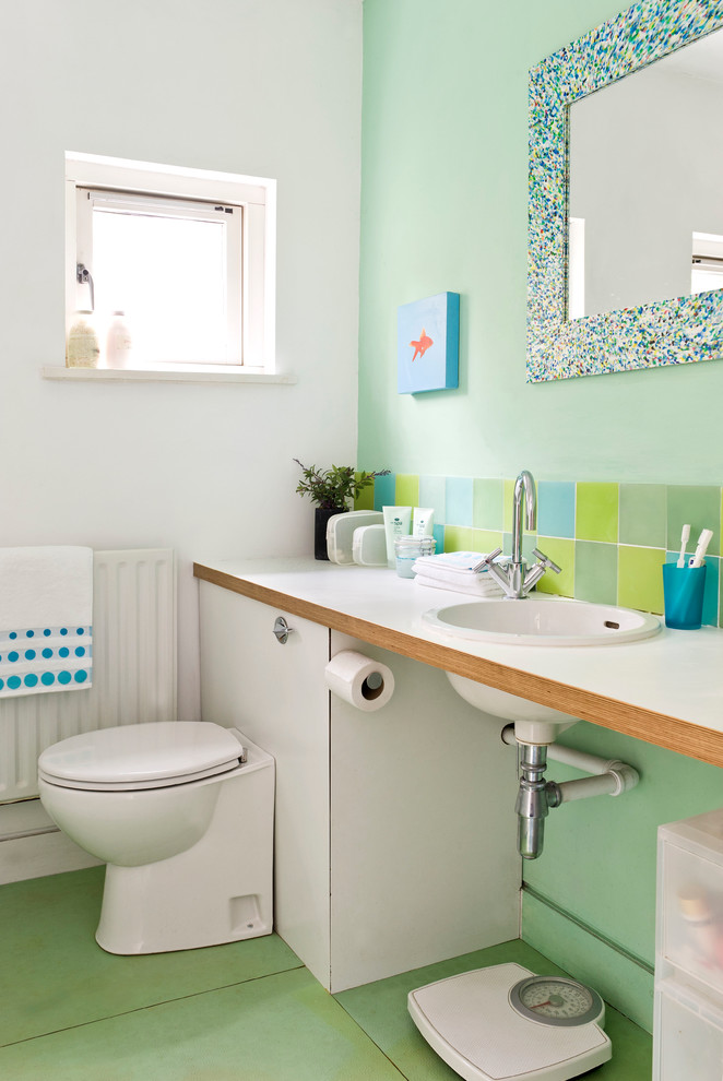 他の地域にあるビーチスタイルのおしゃれな浴室 (オーバーカウンターシンク、木製洗面台、分離型トイレ、緑のタイル、セラミックタイル、緑の壁、セラミックタイルの床、緑の床、白い洗面カウンター) の写真