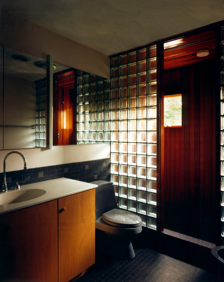 Aménagement d'une salle d'eau moderne en bois brun de taille moyenne avec un placard à porte plane, une douche ouverte, WC à poser, un carrelage gris, un carrelage de pierre, un mur beige, un sol en ardoise et un lavabo intégré.