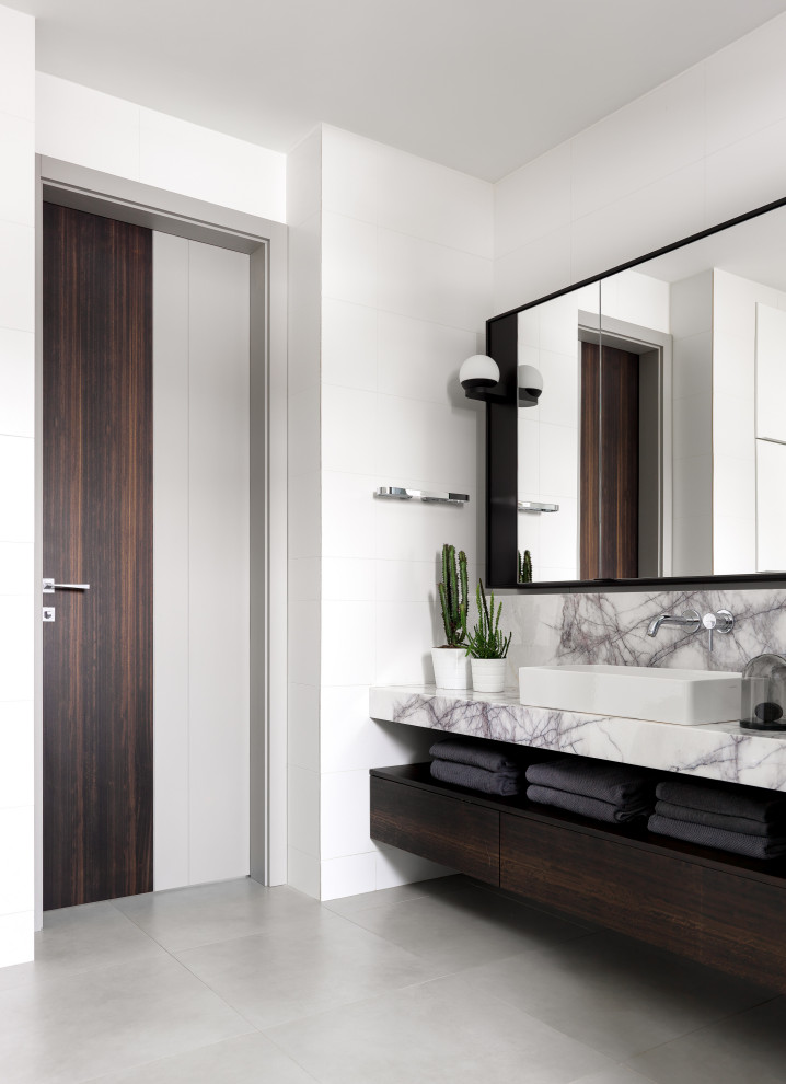 Modernes Badezimmer mit flächenbündigen Schrankfronten, dunklen Holzschränken, weißer Wandfarbe, Aufsatzwaschbecken, grauem Boden, grauer Waschtischplatte, Einzelwaschbecken und schwebendem Waschtisch in Sonstige