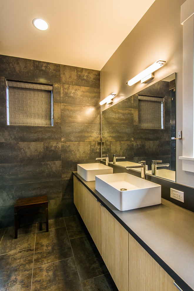 Modelo de cuarto de baño actual con lavabo sobreencimera, armarios con paneles lisos, puertas de armario de madera clara, baldosas y/o azulejos grises y paredes beige