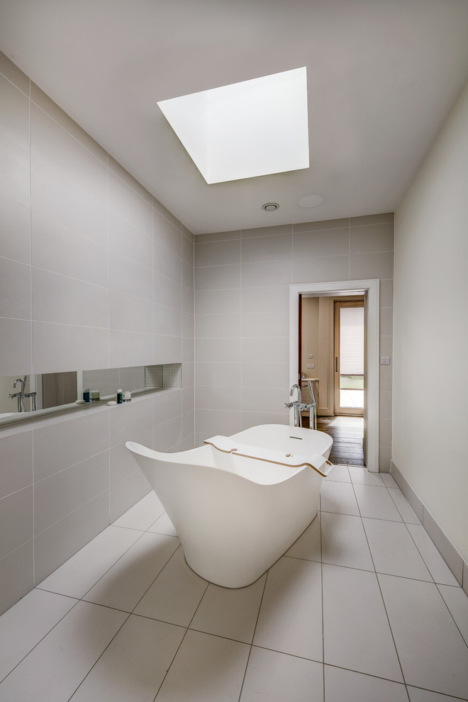 Réalisation d'une salle de bain grise et blanche design avec une baignoire indépendante et un mur gris.