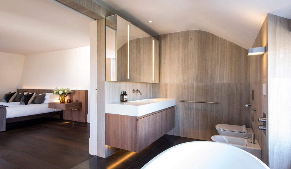 Bild på ett stort funkis en-suite badrum, med släta luckor, skåp i mellenmörkt trä, ett fristående badkar, en vägghängd toalettstol, ett avlångt handfat och bänkskiva i akrylsten
