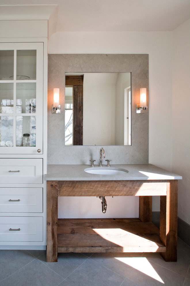 Foto de cuarto de baño costero con lavabo bajoencimera, paredes blancas, puertas de armario con efecto envejecido, armarios abiertos y encimeras grises