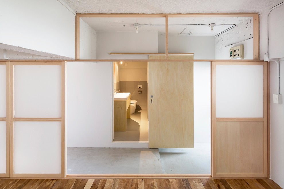 Modernes Badezimmer mit Toilette mit Aufsatzspülkasten, hellen Holzschränken und weißer Wandfarbe in Tokio