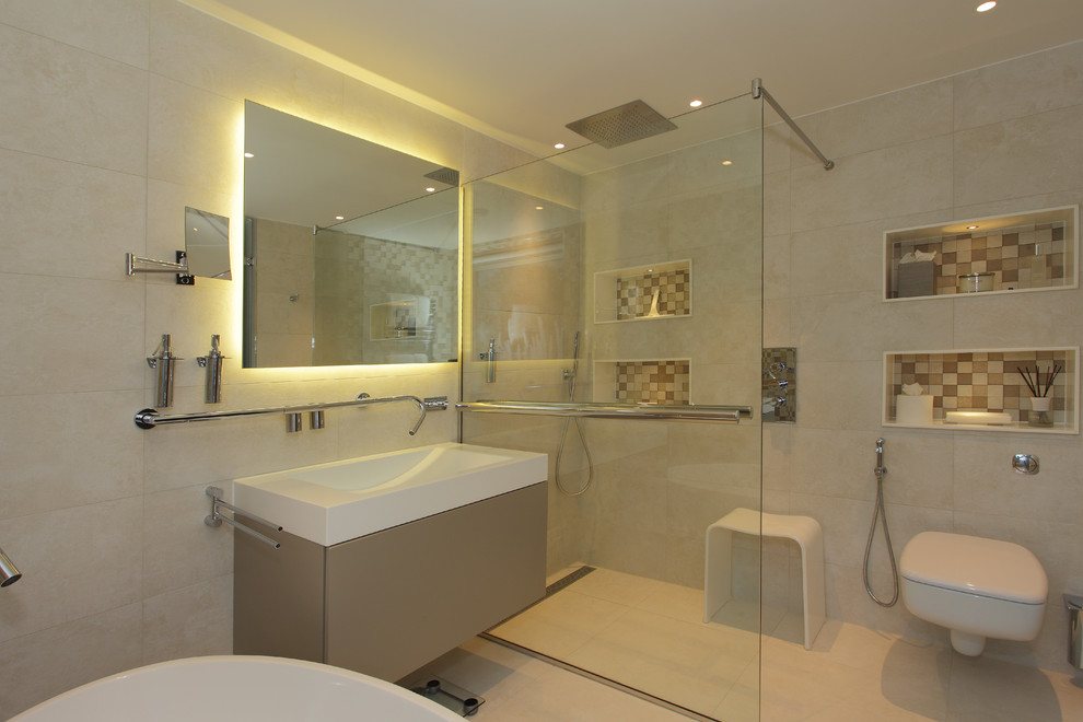 This is an example of a large contemporary family bathroom in Hampshire with freestanding cabinets, white cabinets, a freestanding bath, a walk-in shower, a wall mounted toilet, white tiles, porcelain tiles, white walls, porcelain flooring, a console sink and solid surface worktops.