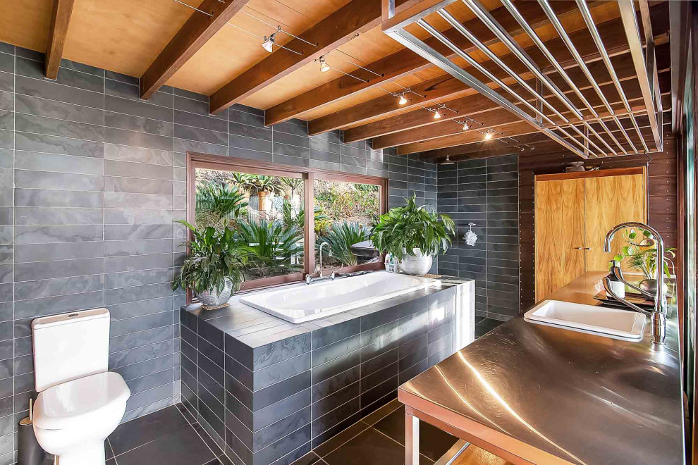 Immagine di una stanza da bagno padronale tropicale con vasca da incasso, doccia aperta, piastrelle grigie, pareti grigie, lavabo da incasso, top in acciaio inossidabile, pavimento grigio e doccia aperta