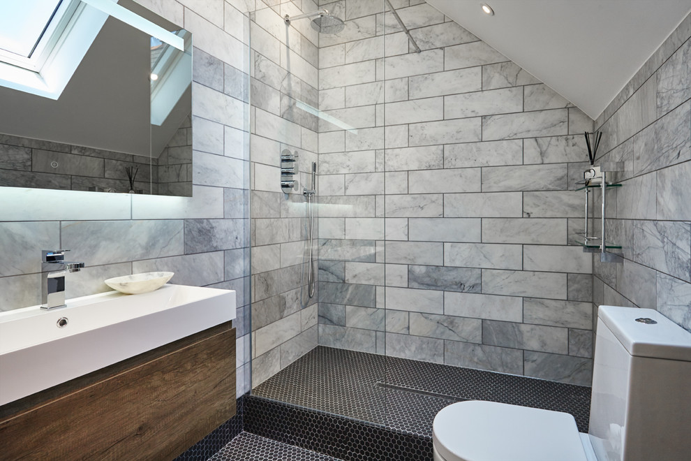 Idées déco pour une petite salle de bain contemporaine avec un placard à porte plane, des portes de placard marrons, un espace douche bain, WC à poser, du carrelage en marbre, un mur gris, un sol noir et aucune cabine.