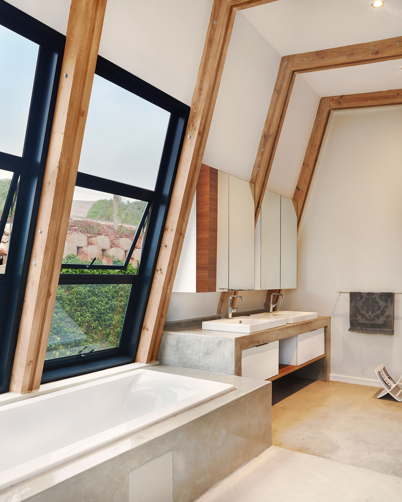 Diseño de cuarto de baño contemporáneo con encimera de cemento, bañera encastrada y ducha abierta