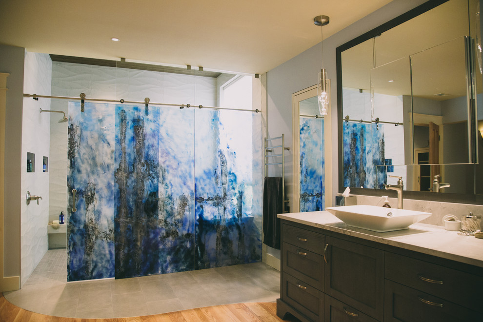 This is an example of an expansive contemporary ensuite wet room bathroom in Portland with shaker cabinets, dark wood cabinets, a freestanding bath, a one-piece toilet, blue tiles, porcelain tiles, blue walls, medium hardwood flooring, a vessel sink, quartz worktops, grey floors and a sliding door.
