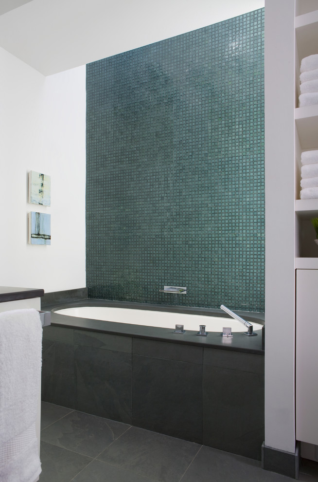 На фото: главная ванная комната среднего размера в стиле неоклассика (современная классика) с плоскими фасадами, белыми фасадами, полновстраиваемой ванной, душем в нише, зеленой плиткой, стеклянной плиткой, белыми стенами, полом из керамической плитки и серой столешницей с