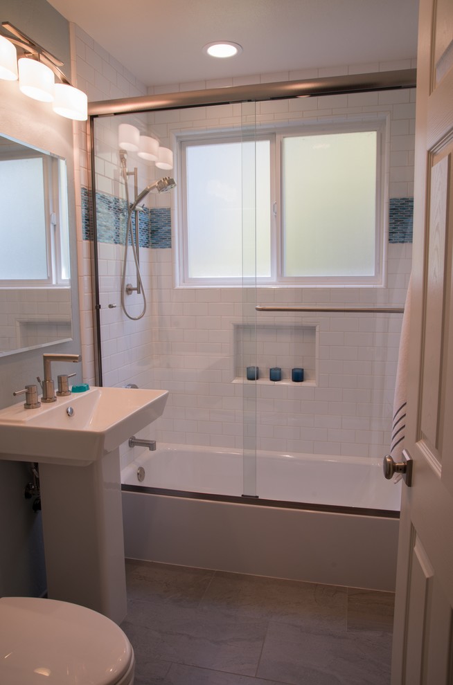 Klassisk inredning av ett mellanstort badrum, med ett badkar i en alkov, en dusch/badkar-kombination, blå kakel, vit kakel, tunnelbanekakel, grå väggar, klinkergolv i porslin och ett piedestal handfat