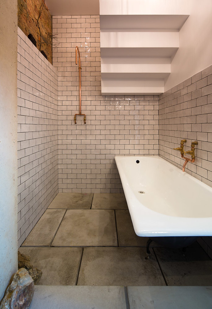 Urban white tile and ceramic tile concrete floor bathroom photo in London with white walls