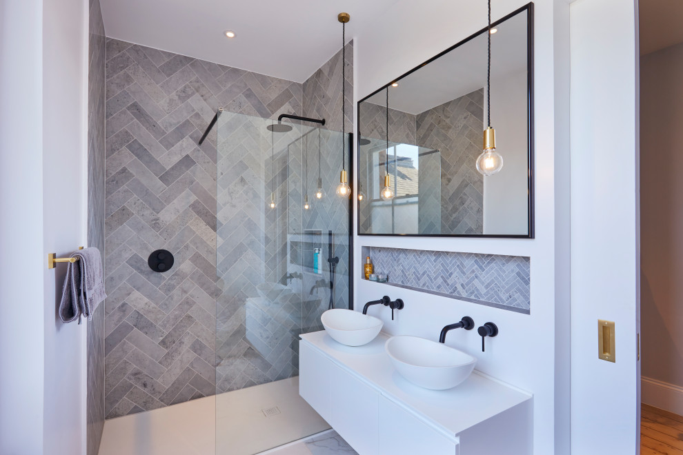 Modern inredning av ett mellanstort vit vitt badrum med dusch, med släta luckor, vita skåp, en öppen dusch, grå kakel, porslinskakel, vita väggar, klinkergolv i porslin, ett fristående handfat, laminatbänkskiva, dusch med gångjärnsdörr och grått golv