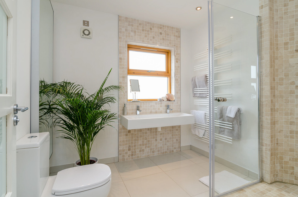 На фото: главная ванная комната среднего размера в современном стиле с унитазом-моноблоком, бежевой плиткой, белыми стенами, полом из керамической плитки и подвесной раковиной с