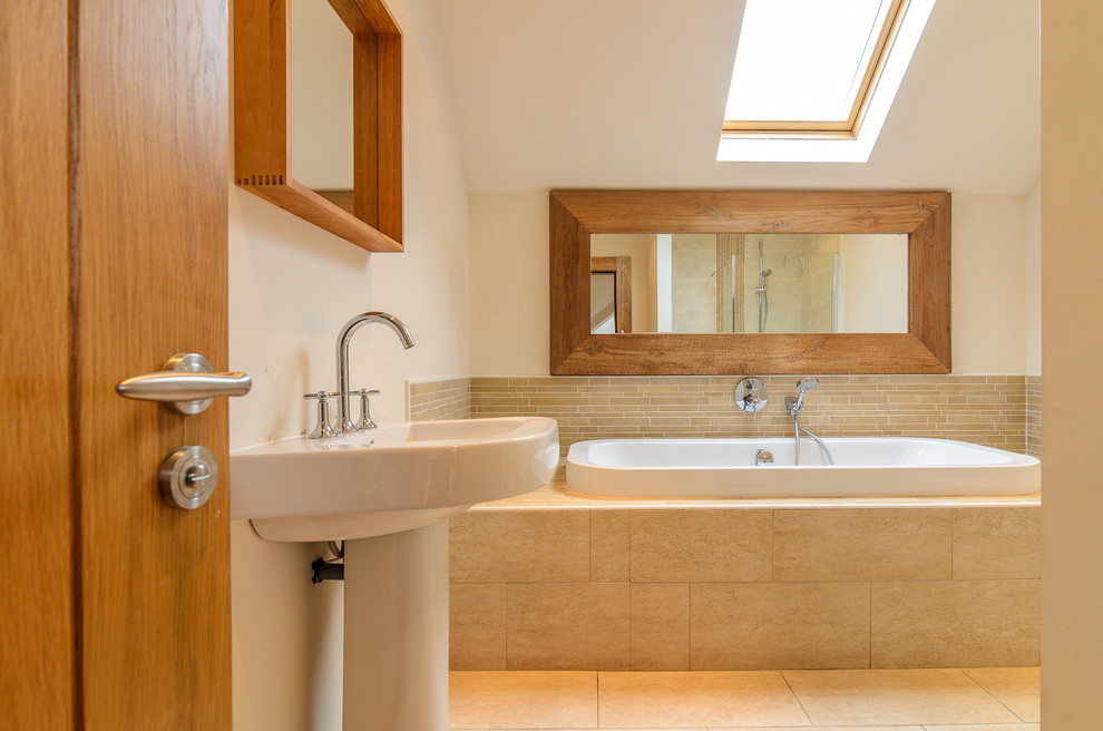 Diseño de cuarto de baño tradicional con lavabo con pedestal, bañera encastrada, baldosas y/o azulejos beige, azulejos en listel, suelo de travertino y paredes beige