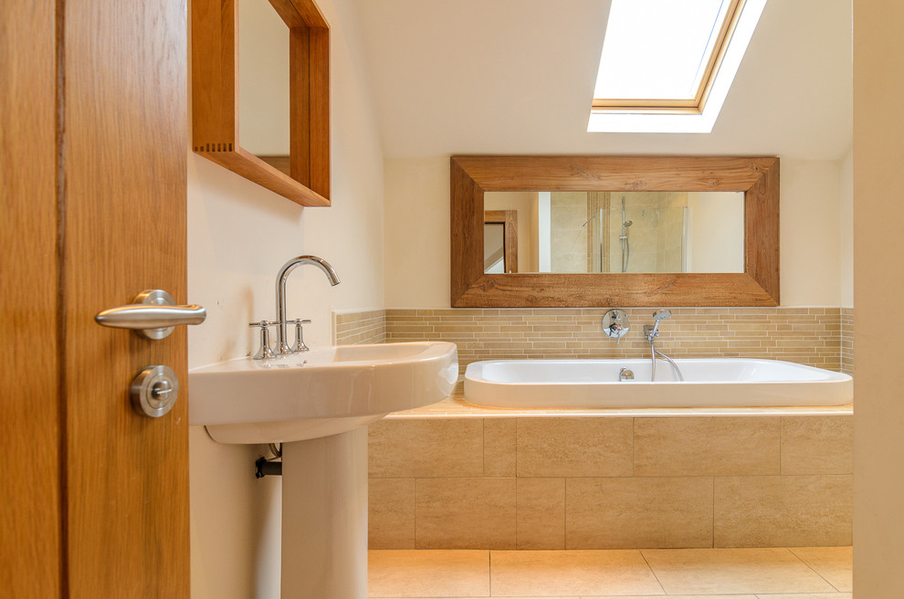 Example of a classic beige tile and matchstick tile travertine floor drop-in bathtub design in Belfast with a pedestal sink and beige walls