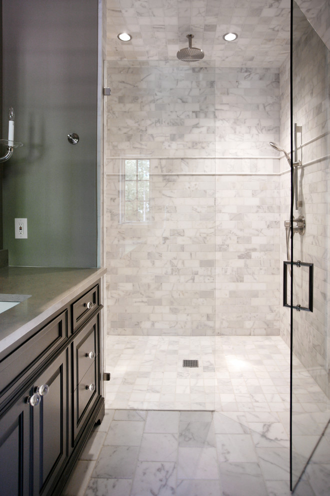 Exemple d'une salle de bain tendance de taille moyenne avec un lavabo encastré, un placard avec porte à panneau encastré, des portes de placard noires, un plan de toilette en calcaire, WC à poser, un carrelage blanc, un carrelage de pierre, un mur gris et un sol en marbre.