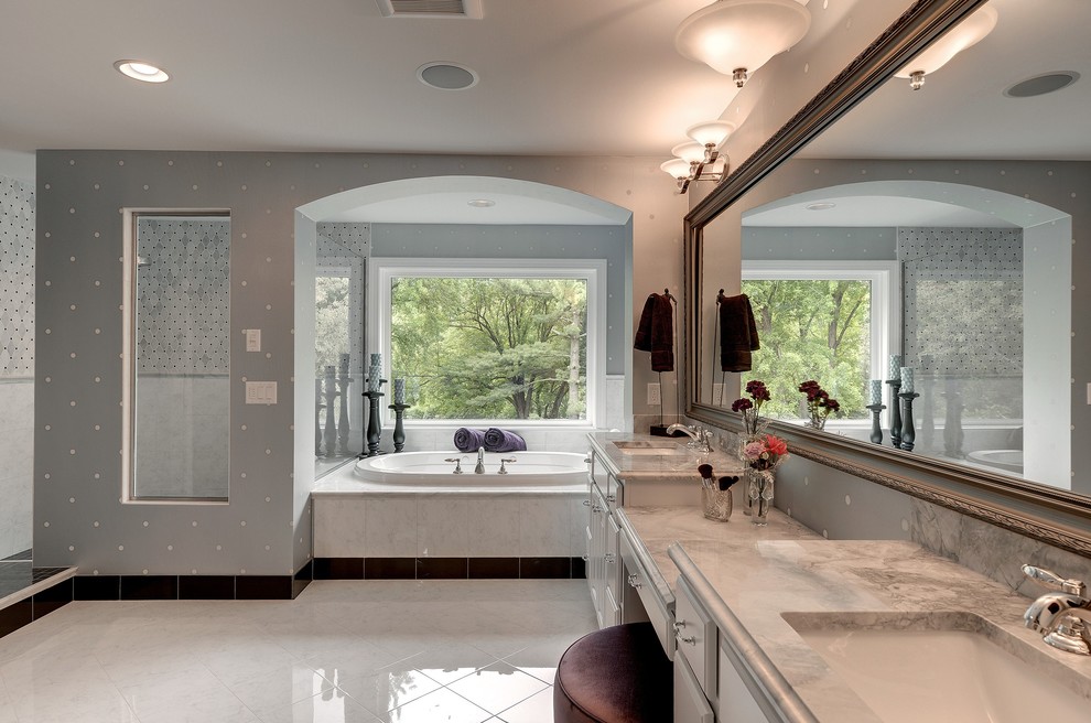 Klassisk inredning av ett badrum, med ett undermonterad handfat, vita skåp, ett platsbyggt badkar, en öppen dusch, vit kakel och med dusch som är öppen