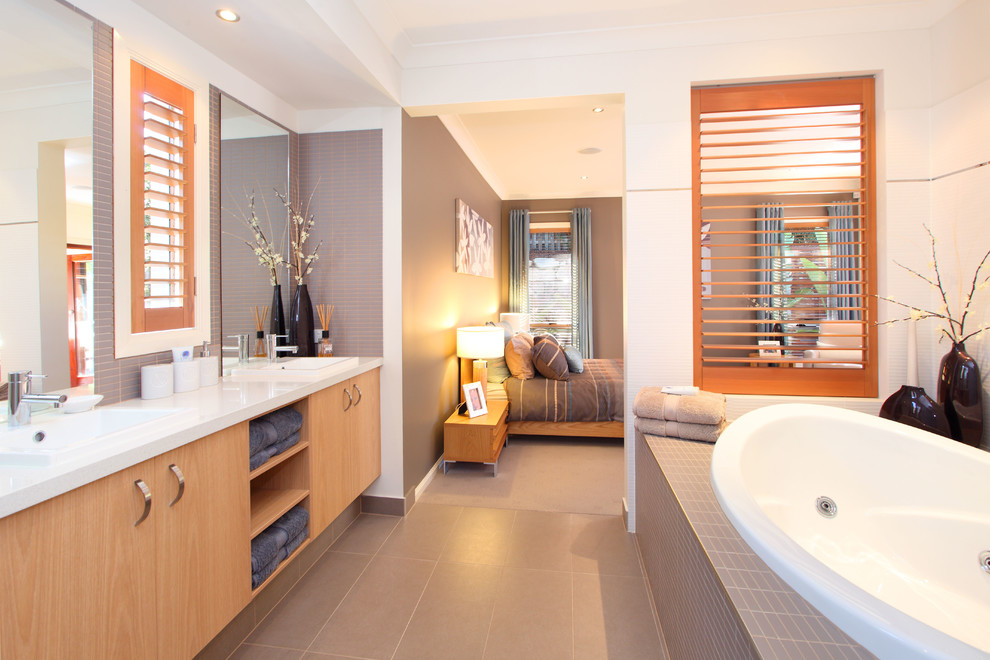 На фото: ванная комната в современном стиле с плоскими фасадами, светлыми деревянными фасадами, накладной ванной, серой плиткой и белой столешницей с