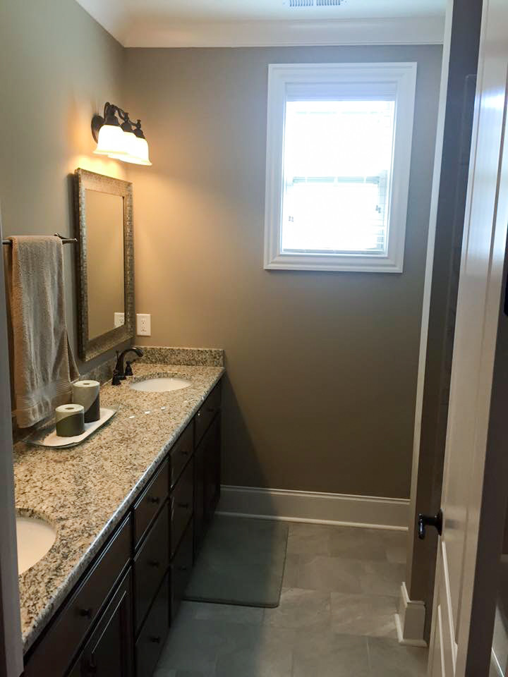 Photo of a traditional bathroom in Raleigh with dark wood cabinets, green walls, porcelain flooring, a submerged sink, granite worktops and grey floors.