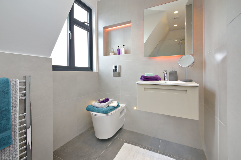 Example of a mid-sized minimalist master gray tile and porcelain tile porcelain tile and gray floor doorless shower design in London with flat-panel cabinets, beige cabinets, a wall-mount toilet, gray walls, a wall-mount sink, solid surface countertops, a hinged shower door and white countertops