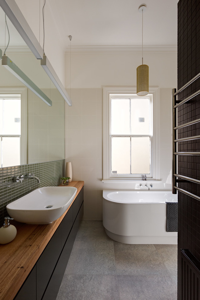 メルボルンにあるコンテンポラリースタイルのおしゃれな浴室 (フラットパネル扉のキャビネット、黒いキャビネット、木製洗面台、置き型浴槽、緑のタイル、ブラウンの洗面カウンター) の写真