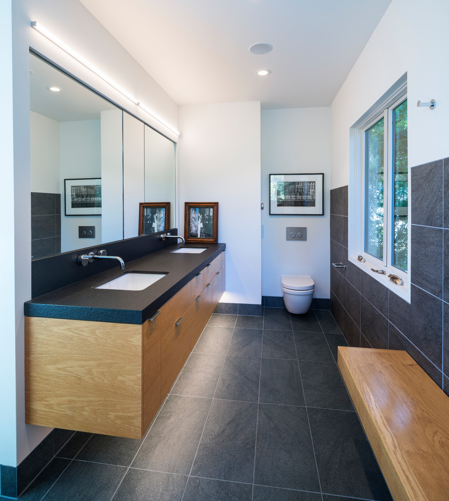 Стильный дизайн: главная ванная комната среднего размера в стиле модернизм с плоскими фасадами, фасадами цвета дерева среднего тона, инсталляцией, серой плиткой, белыми стенами, врезной раковиной, черной столешницей и серым полом - последний тренд