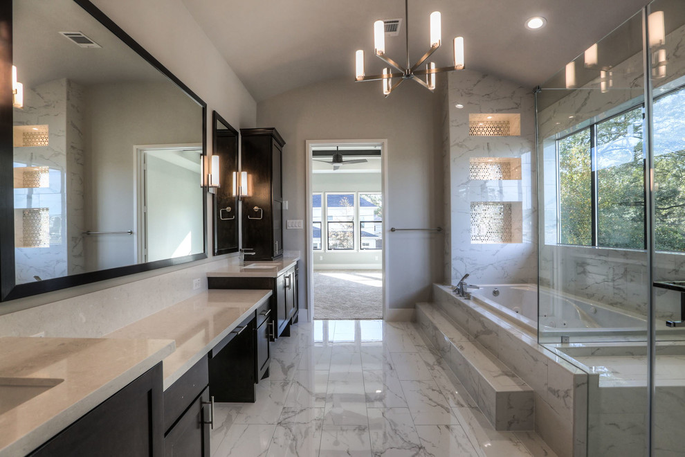 Large modern ensuite bathroom in Houston with recessed-panel cabinets, dark wood cabinets, a hot tub, a corner shower, a one-piece toilet, grey tiles, ceramic tiles, white walls, ceramic flooring, a submerged sink, engineered stone worktops, grey floors and a hinged door.