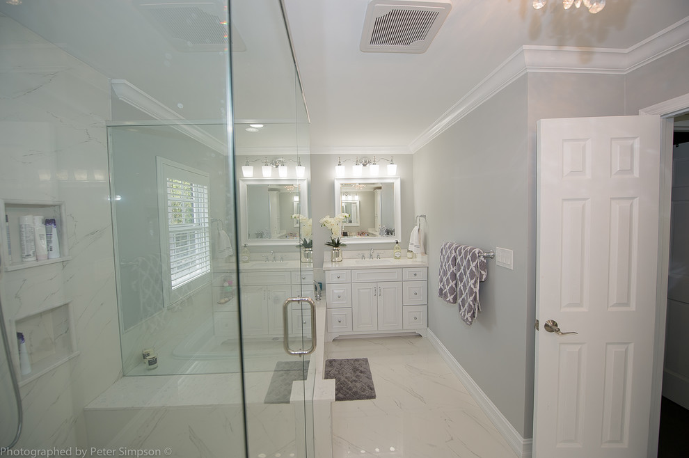 Стильный дизайн: большая главная ванная комната в стиле неоклассика (современная классика) с фасадами островного типа, белыми фасадами, накладной ванной, двойным душем, раздельным унитазом, белой плиткой, мраморной плиткой, серыми стенами, мраморным полом, врезной раковиной, мраморной столешницей, белым полом и душем с распашными дверями - последний тренд