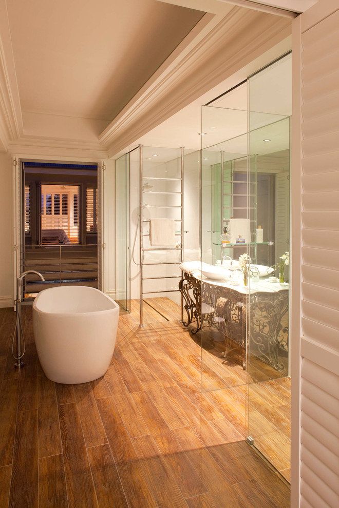 Cette image montre une salle de bain design avec une baignoire indépendante et un sol en bois brun.