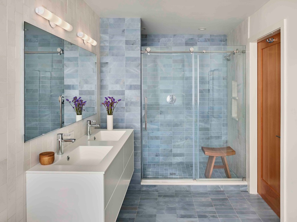 На фото: главная ванная комната среднего размера в современном стиле с плоскими фасадами, белыми фасадами, двойным душем, унитазом-моноблоком, синей плиткой, мраморной плиткой, синими стенами, мраморным полом, монолитной раковиной, столешницей из искусственного камня, синим полом и душем с раздвижными дверями с