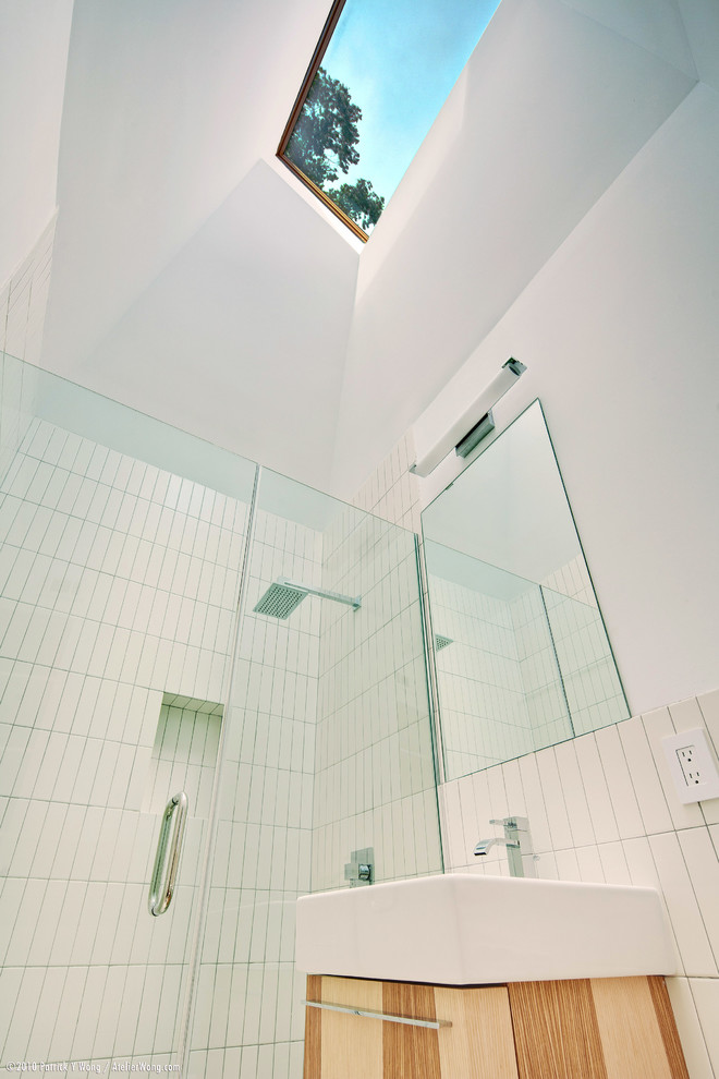 Idee per una piccola stanza da bagno moderna con lavabo a consolle, ante lisce, ante in legno chiaro, WC monopezzo, piastrelle bianche, piastrelle in ceramica, pareti bianche, pavimento con piastrelle in ceramica e doccia a filo pavimento
