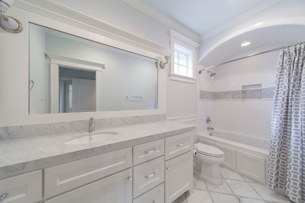 Inspiration för stora klassiska badrum, med luckor med infälld panel, vita skåp, ett badkar i en alkov, en dusch/badkar-kombination, en toalettstol med separat cisternkåpa, vit kakel, tunnelbanekakel, vita väggar, klinkergolv i porslin, ett undermonterad handfat, marmorbänkskiva och dusch med duschdraperi