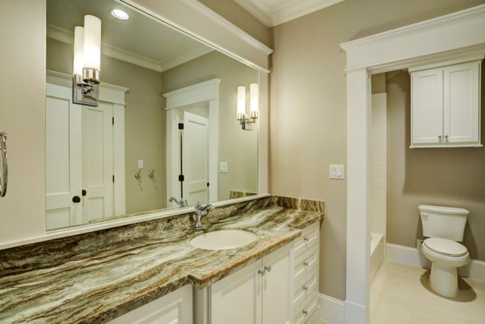 Design ideas for a large classic bathroom in Houston with shaker cabinets, white cabinets, white tiles, stone tiles, grey walls, ceramic flooring, a built-in sink, limestone worktops, a shower/bath combination and a two-piece toilet.
