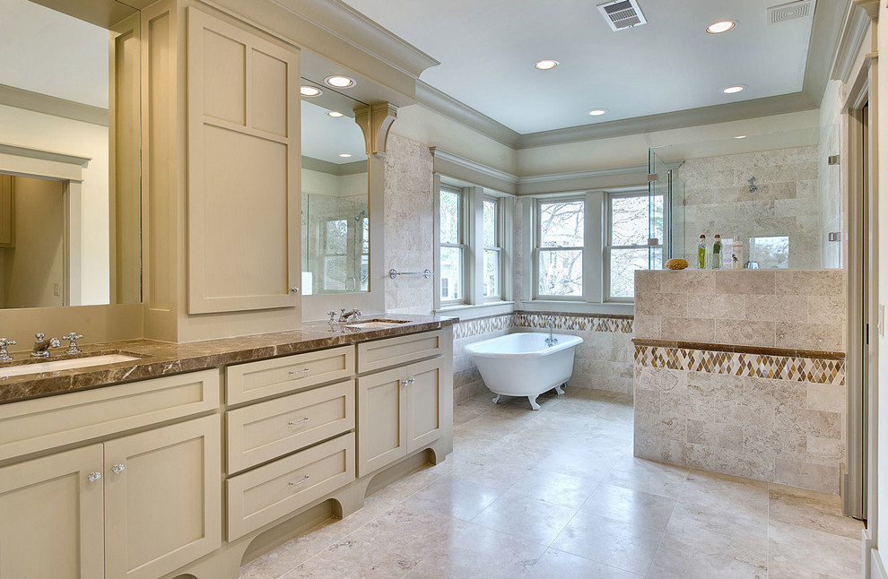 Cette photo montre une salle de bain craftsman avec une baignoire sur pieds, un placard à porte shaker et du carrelage en travertin.