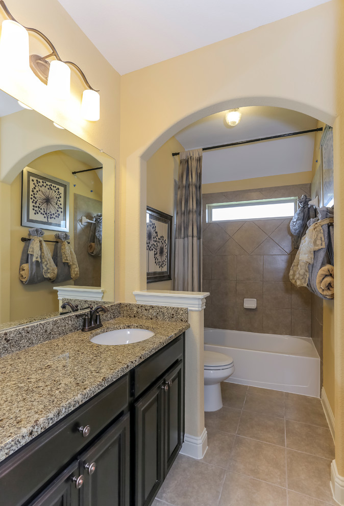 Photo of a medium sized shower room bathroom in Houston with raised-panel cabinets, black cabinets, an alcove bath, a shower/bath combination, beige tiles, porcelain tiles, yellow walls, porcelain flooring, a submerged sink and laminate worktops.