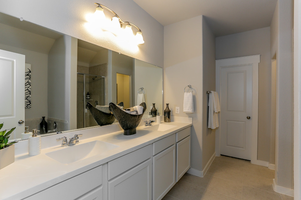 Photo of a medium sized classic ensuite bathroom in Houston with recessed-panel cabinets, white cabinets, an alcove shower, beige tiles, ceramic tiles, beige walls, ceramic flooring, a submerged sink, solid surface worktops, beige floors, a hinged door, white worktops and an alcove bath.