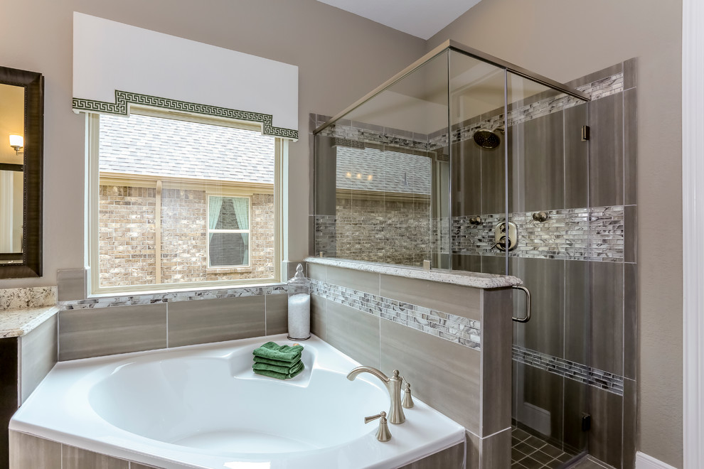 Exemple d'une grande salle de bain principale chic en bois foncé avec un placard avec porte à panneau surélevé, une baignoire d'angle, une douche d'angle, un carrelage gris, un carrelage en pâte de verre, un mur gris, un sol en carrelage de porcelaine, un lavabo encastré et un plan de toilette en granite.