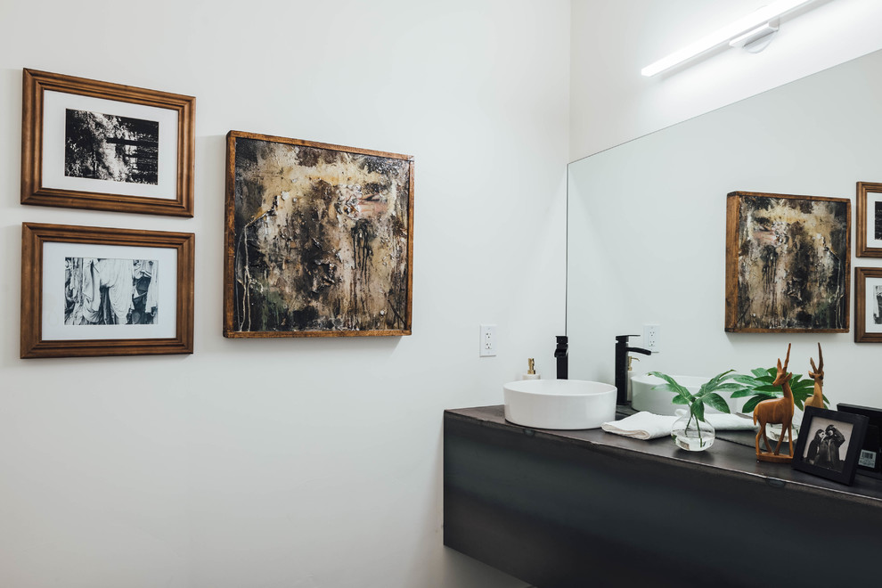 Foto de cuarto de baño contemporáneo con armarios con paneles lisos, puertas de armario negras, paredes blancas, lavabo sobreencimera y encimeras negras