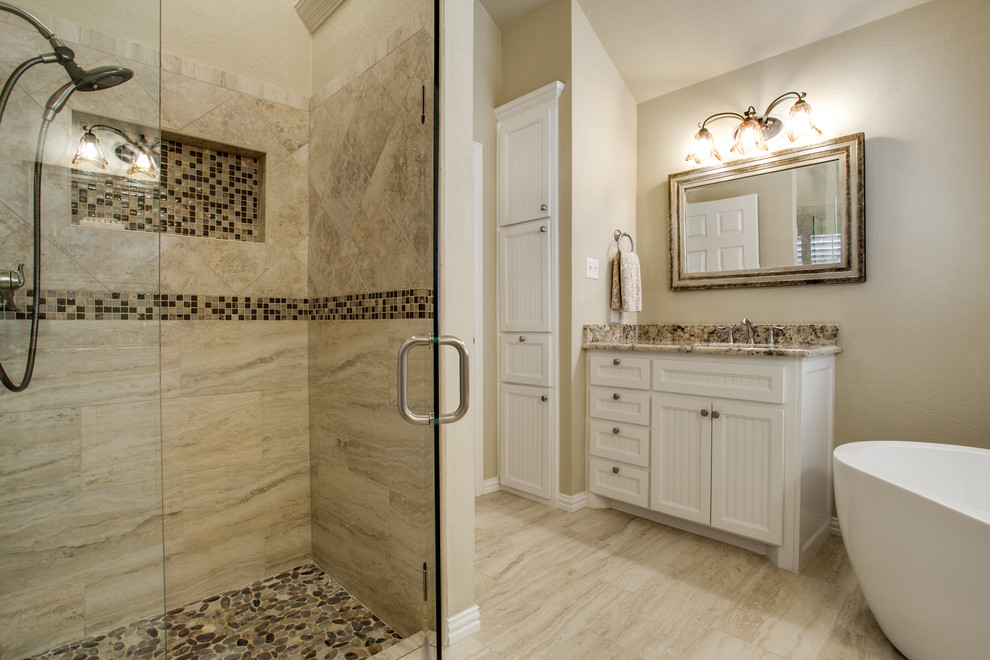 ダラスにある高級なトラディショナルスタイルのおしゃれな浴室 (インセット扉のキャビネット、白いキャビネット、御影石の洗面台、置き型浴槽、マルチカラーのタイル、磁器タイル、トラバーチンの床、ベージュの壁) の写真