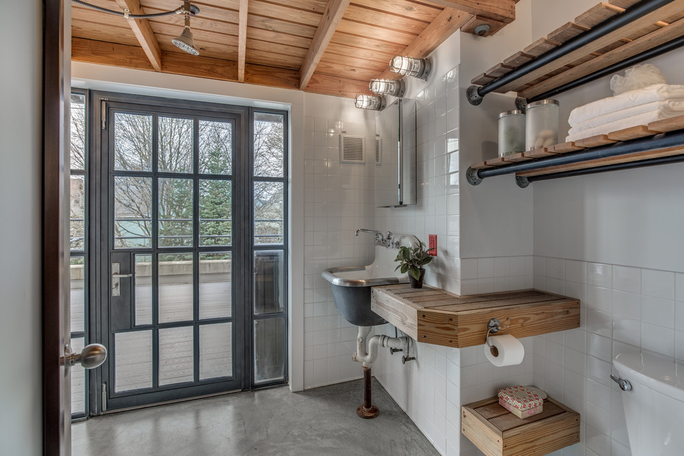 На фото: ванная комната в стиле лофт с белой плиткой, бетонным полом, столешницей из дерева, открытыми фасадами, подвесной раковиной и коричневой столешницей