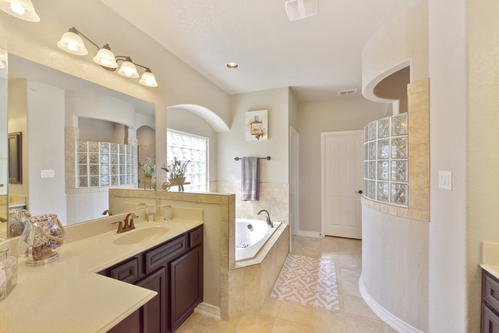 Design ideas for a large traditional ensuite bathroom in Austin with raised-panel cabinets, dark wood cabinets, a built-in bath, beige tiles, ceramic tiles, beige walls, ceramic flooring, an integrated sink, laminate worktops and beige floors.