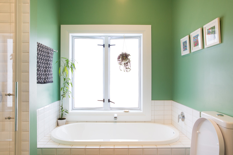オークランドにあるお手頃価格の中くらいなコンテンポラリースタイルのおしゃれなマスターバスルーム (オープンシェルフ、白いキャビネット、一体型トイレ	、緑の壁、壁付け型シンク、白い洗面カウンター、アルコーブ型浴槽、白いタイル) の写真