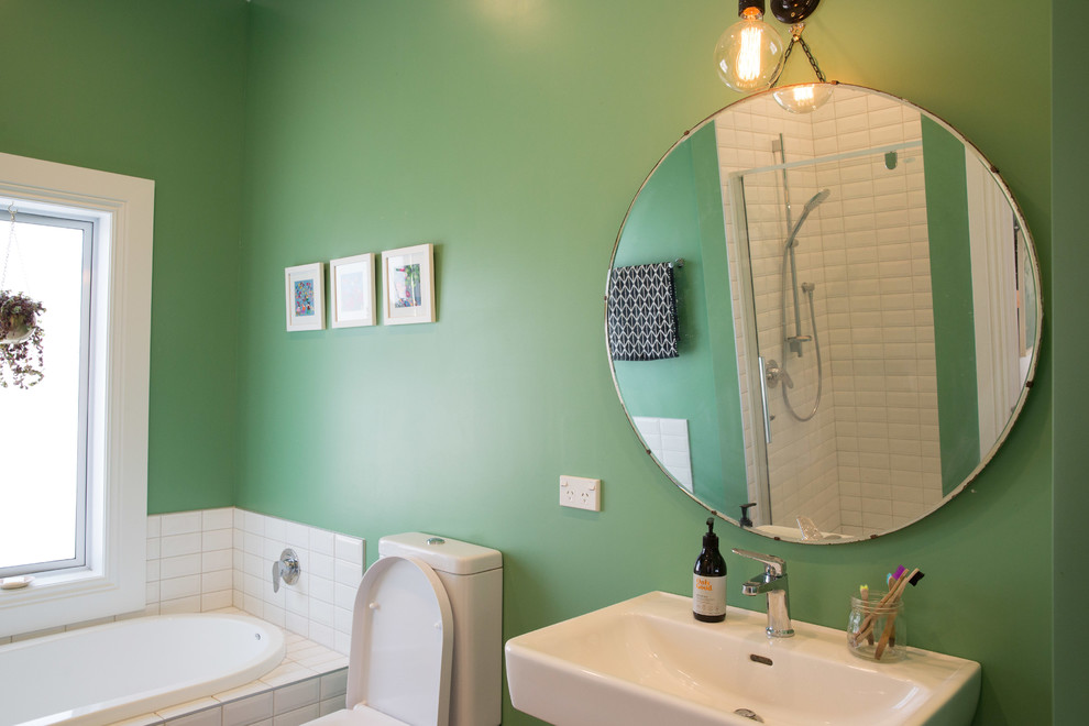 Foto di una stanza da bagno minimal di medie dimensioni con nessun'anta, ante bianche, WC monopezzo, pareti verdi, lavabo sospeso e top bianco