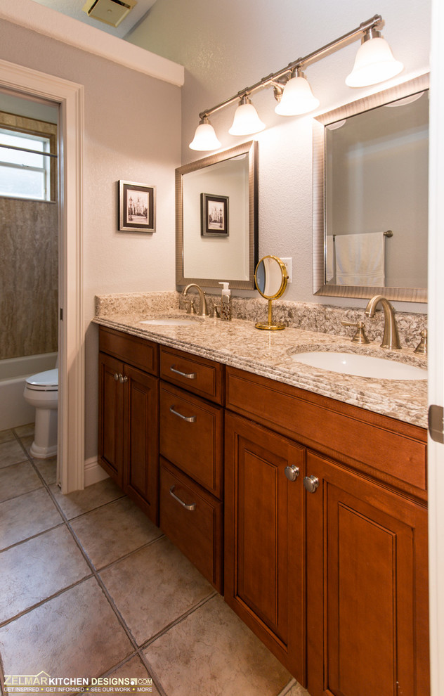 Example of a large classic master beige tile and stone tile travertine floor bathroom design in Orlando with an undermount sink, raised-panel cabinets, medium tone wood cabinets and quartz countertops