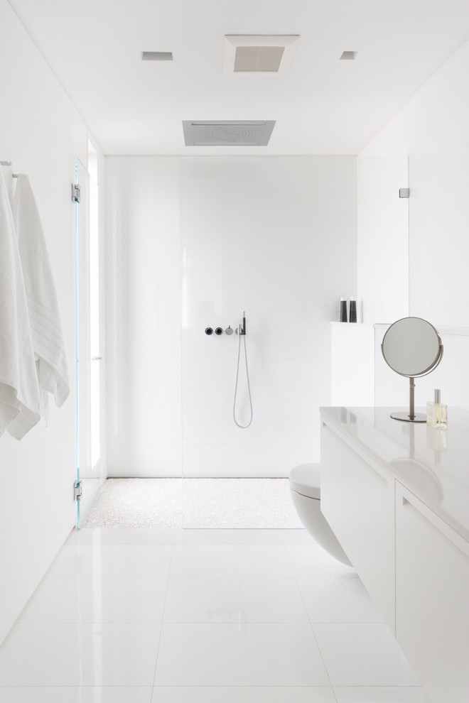 На фото: ванная комната в современном стиле с врезной раковиной, плоскими фасадами, белыми фасадами, столешницей из искусственного кварца, открытым душем, инсталляцией, белой плиткой, белыми стенами, душевой кабиной и открытым душем