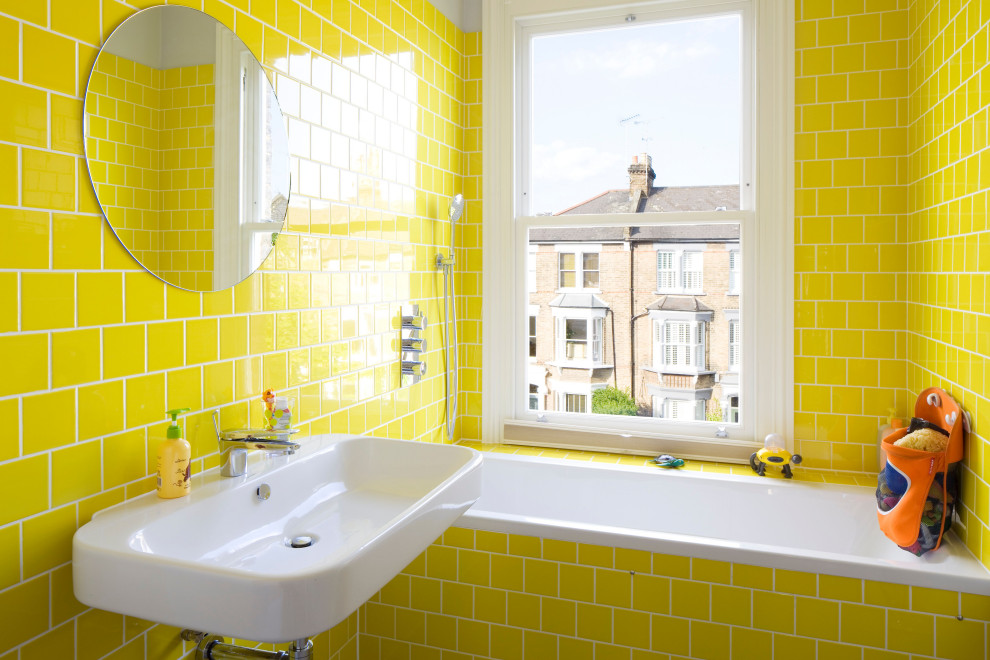 Inspiration för små badrum för barn, med ett badkar i en alkov, en dusch/badkar-kombination, en toalettstol med hel cisternkåpa, gul kakel, keramikplattor, grå väggar, klinkergolv i porslin, ett väggmonterat handfat och grått golv