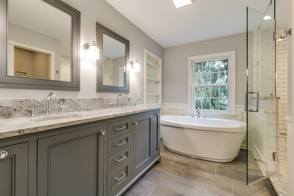 Foto på ett stort lantligt flerfärgad en-suite badrum, med luckor med profilerade fronter, grå skåp, ett fristående badkar, en dusch i en alkov, grå väggar, klinkergolv i porslin, ett undermonterad handfat, granitbänkskiva, grått golv och dusch med gångjärnsdörr