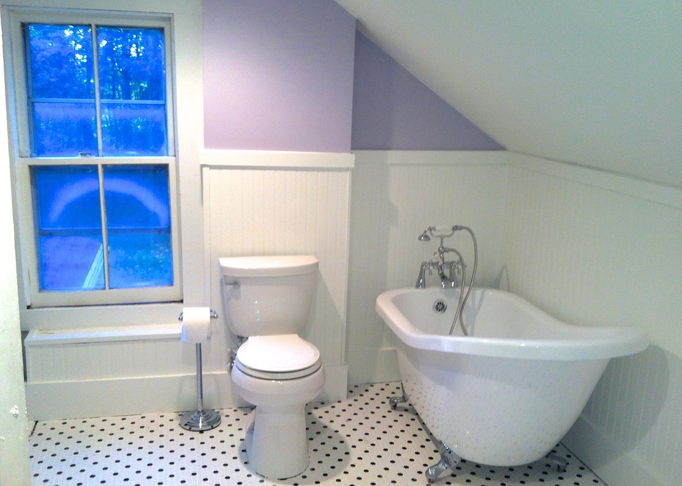Inredning av ett lantligt mellanstort badrum, med luckor med profilerade fronter, vita skåp, bänkskiva i akrylsten, ett badkar med tassar, en hörndusch, en toalettstol med separat cisternkåpa, vit kakel, tunnelbanekakel, lila väggar och klinkergolv i keramik